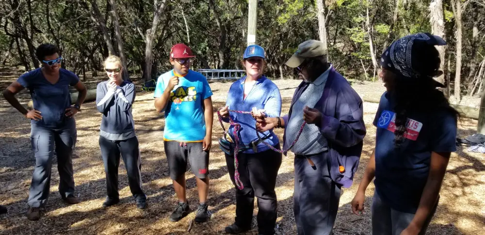 Group outdoors learning rope safety techniques