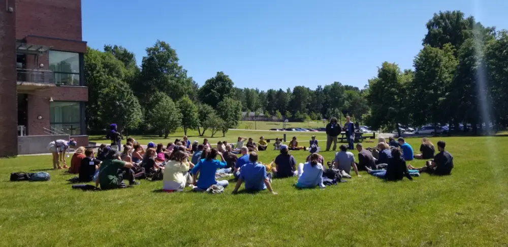 Group of people seated in grassy outdoor circle