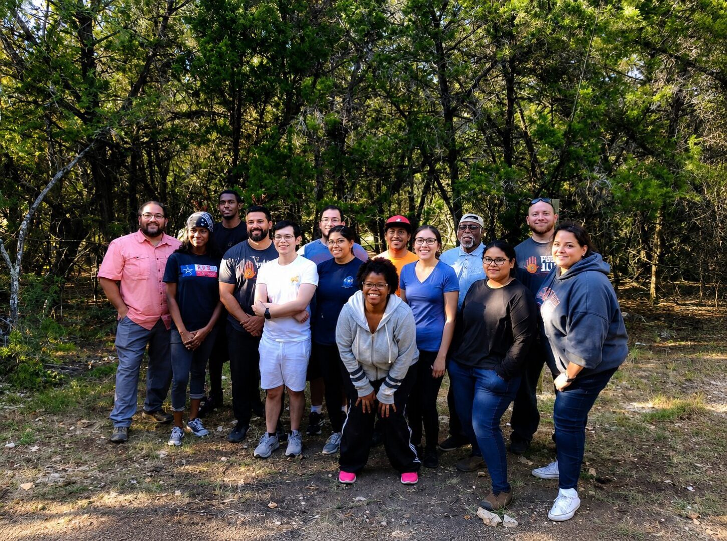 Group of smiling people posing outdoors in woods