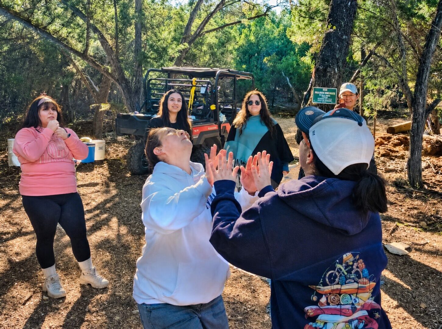 People clapping game in wooded park