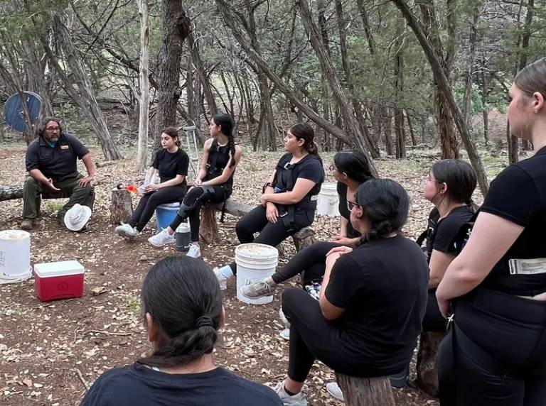 Instructor leading outdoor group meeting in woods