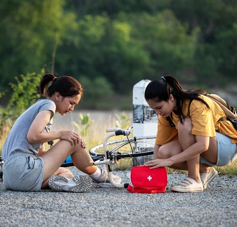 Women providing first aid by fallen bicycle