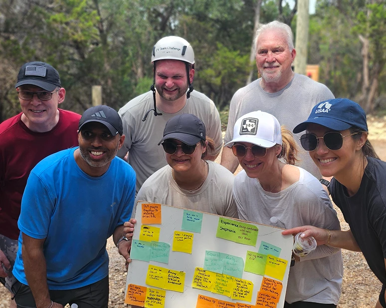 Smiling outdoor team displaying sticky-note board
