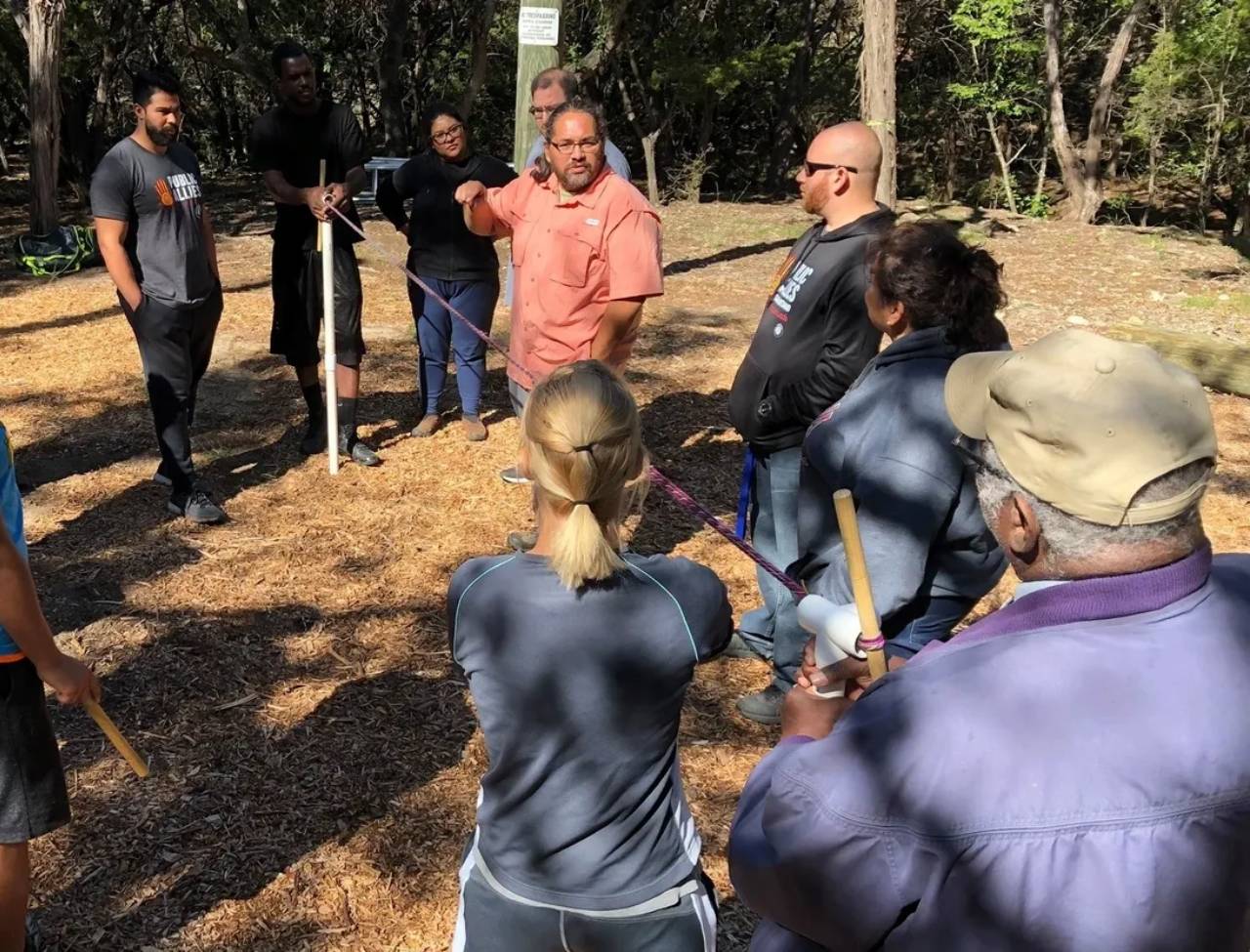 Group standing in wooded area listening to instructor