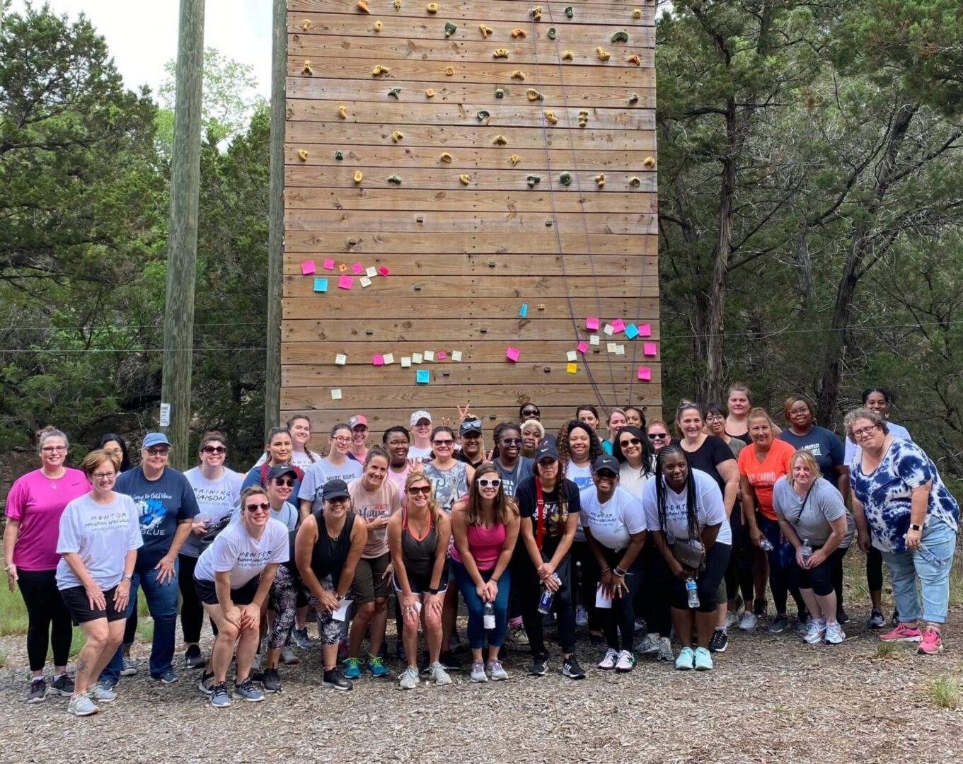 Large group posing before outdoor climbing wall