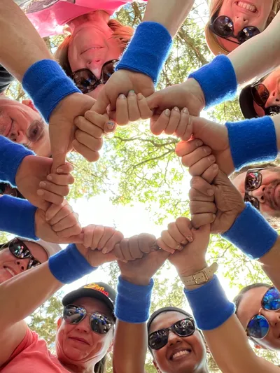 Smiling group forming circle, joined hands, blue wristbands
